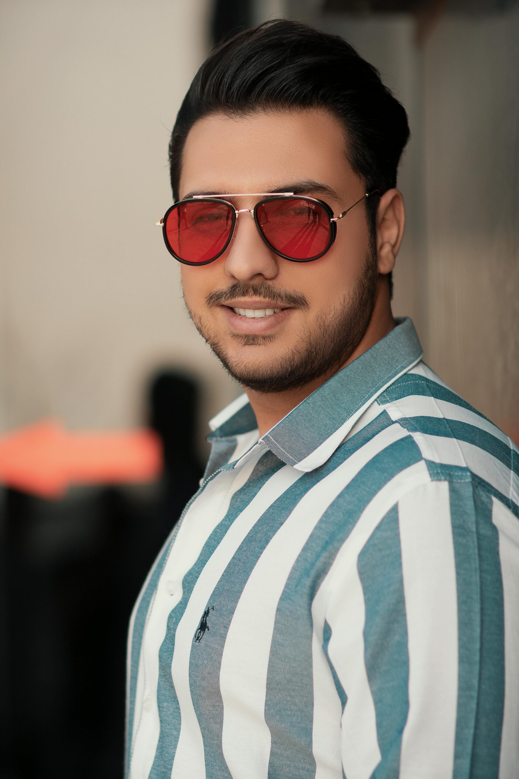 Portrait of a fashionable man wearing red sunglasses and a striped shirt. Stylish urban look.