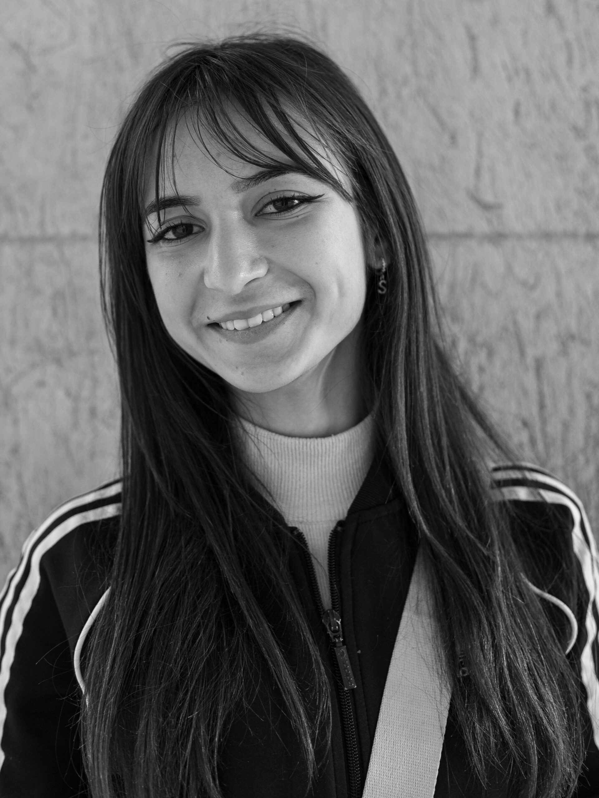 Black and white portrait showing a young woman smiling in casual attire.